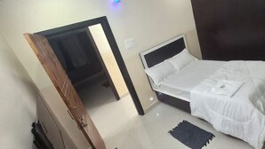 Ein Schlafzimmer mit einem Bett, einem dunkelbraunen Kopfteil, einer weißen Bettdecke und einem kleinen dunklen Teppich.