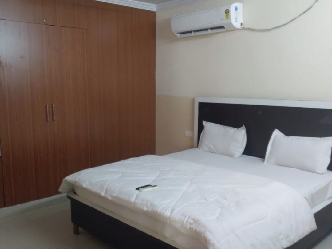 A bedroom with a bed, a wardrobe, and an air conditioning unit.