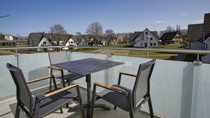 Een balkon met een tafel en stoelen, met uitzicht op een woonwijk met huizen en een heldere lucht.