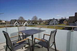 Ein Balkon mit Tisch und Stühlen, der auf einen Wohnbereich mit Häusern blickt.