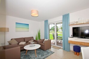 Ein modernes Wohnzimmer mit Sofa, Couchtisch und Flachbildfernseher.