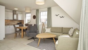 En moderne stue med sofa, sofabord og spiseplads med stole og bord.