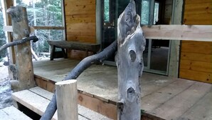 Une terrasse en bois agrémentée d’un banc rustique et d’un poteau en bois original.
