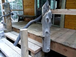 A wooden deck with a rustic bench and a unique wooden post.