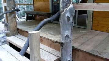 A wooden deck with a rustic bench and a unique wooden post.