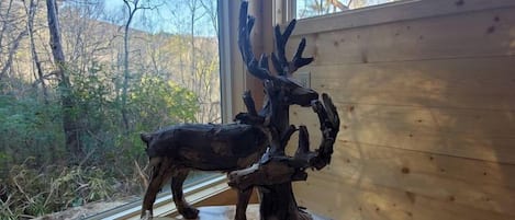 A wooden interior with a large window, a carved deer head, and a drum on a table.