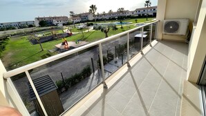 Un balcón con vistas a un parque infantil, una piscina y edificios residenciales.