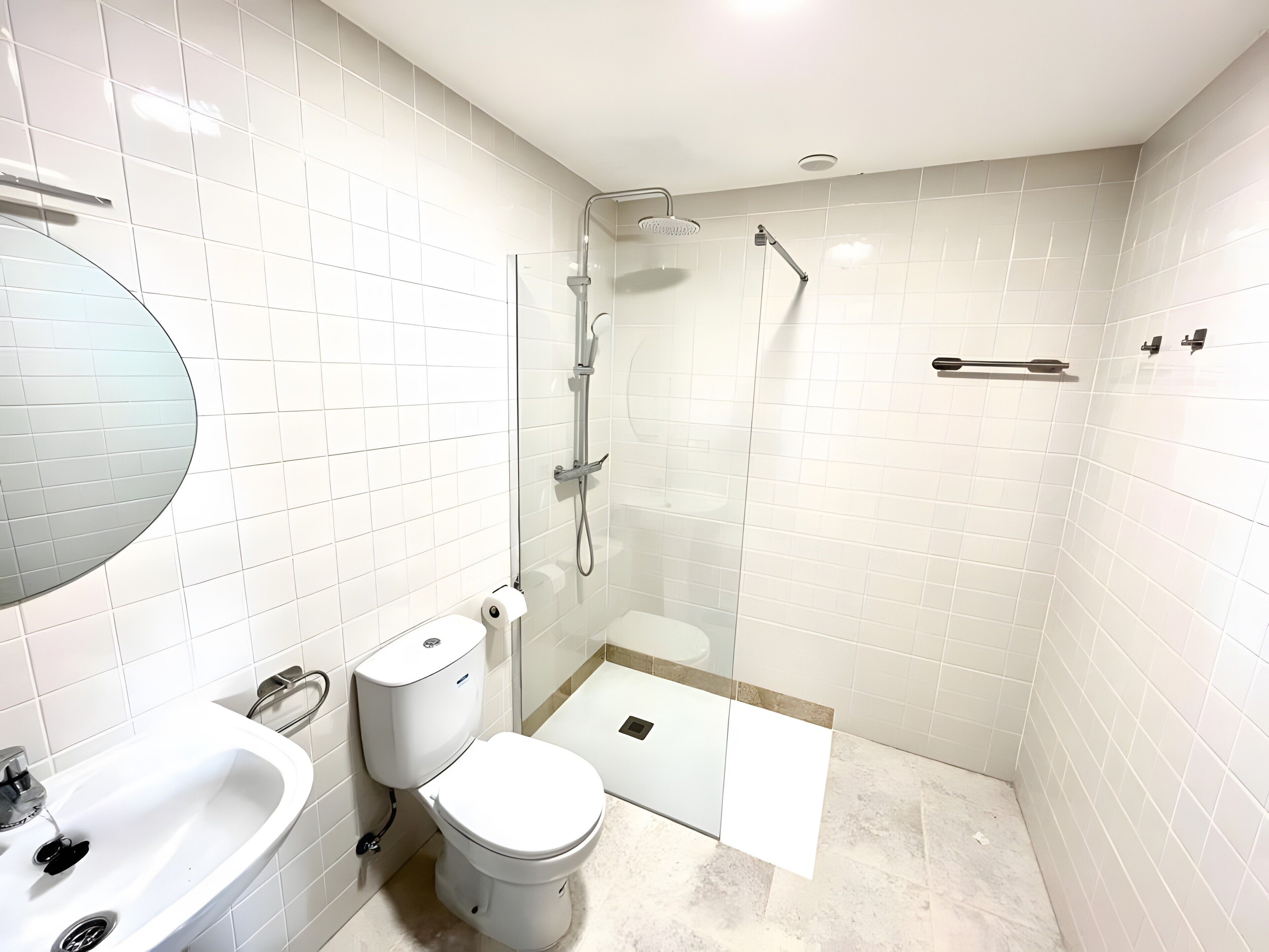 A modern bathroom with a toilet, sink, and glass-enclosed shower area.