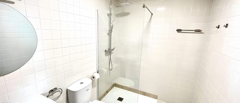 A modern bathroom with a toilet, sink, and glass-enclosed shower area.
