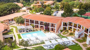 Um resort com piscina central, vários quartos de hóspedes e quadra de tênis.