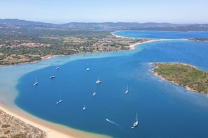 An aerial view of a coastal area with clear blue waters, several boats, and a sandy beach. - Ideal for two people, the Mono Classic is the perfect choice for those seeking a cozy space with meticulous attention to detail. This unique space features an elegant double bed, a modern bathroom with shower, and a fully equipped kitchenette, designed f (Costa Serena - Palau)