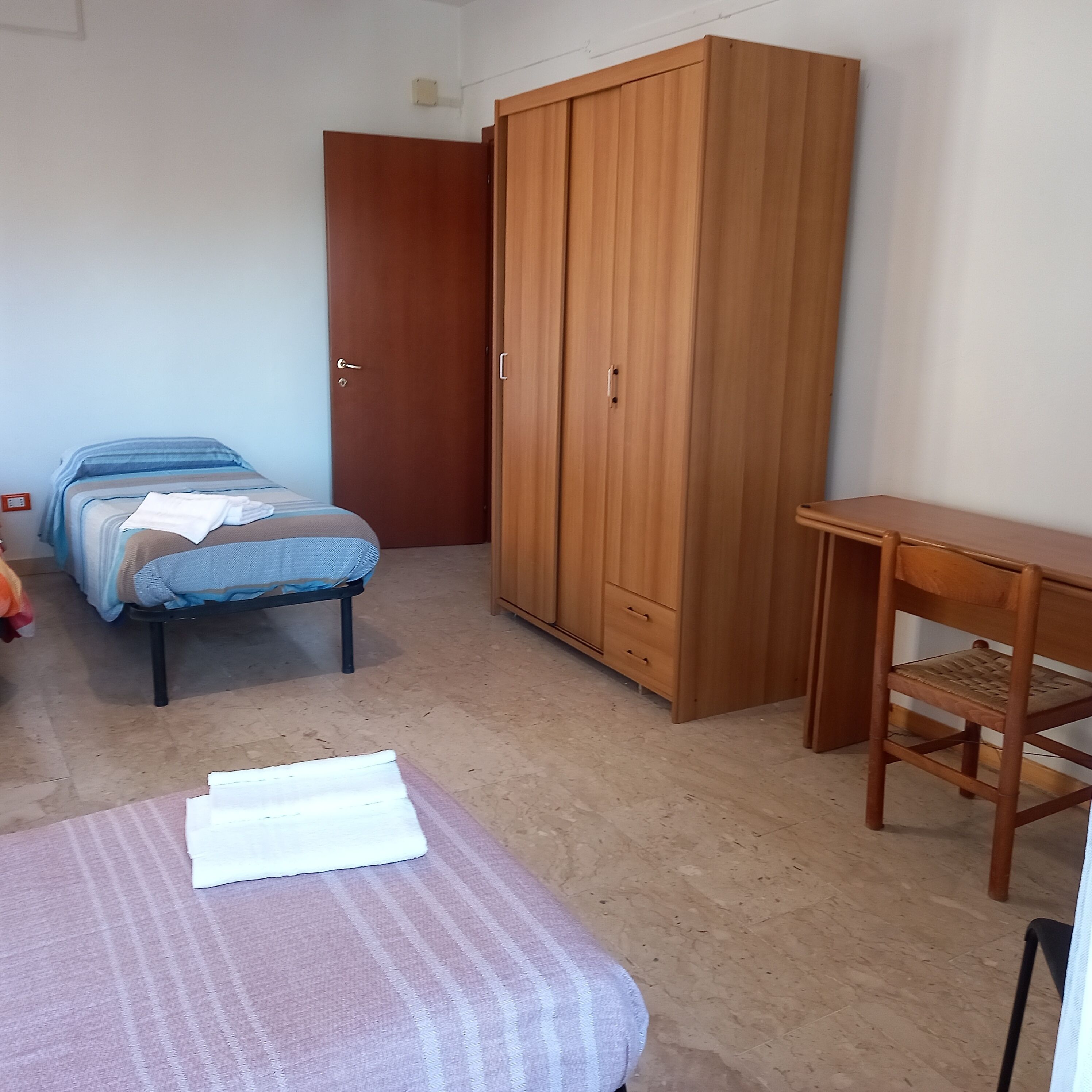Ein Schlafzimmer mit Bett, Kleiderschrank, Schreibtisch und Stuhl.