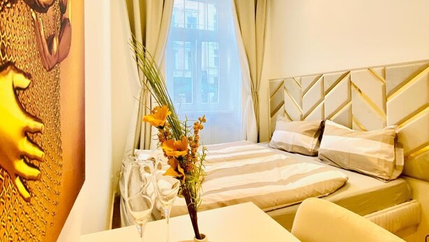 A hotel room with a bed, a sofa, a table with a vase and wine glasses, and a decorative wall. - Charming 4 Bedroom Apartment Ottakring (Vienna)