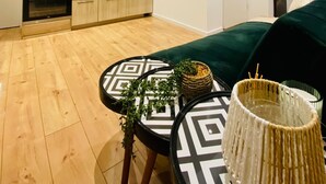 A compact living space with a kitchenette, a dining area with a table and chairs, and a bed with a green cover. - Charming 4 Bedroom Apartment Ottakring (Vienna)