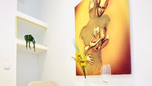 A dining area with a white table, a white chair, a vase with flowers, and two wine glasses. - Charming 4 Bedroom Apartment Ottakring (Vienna)
