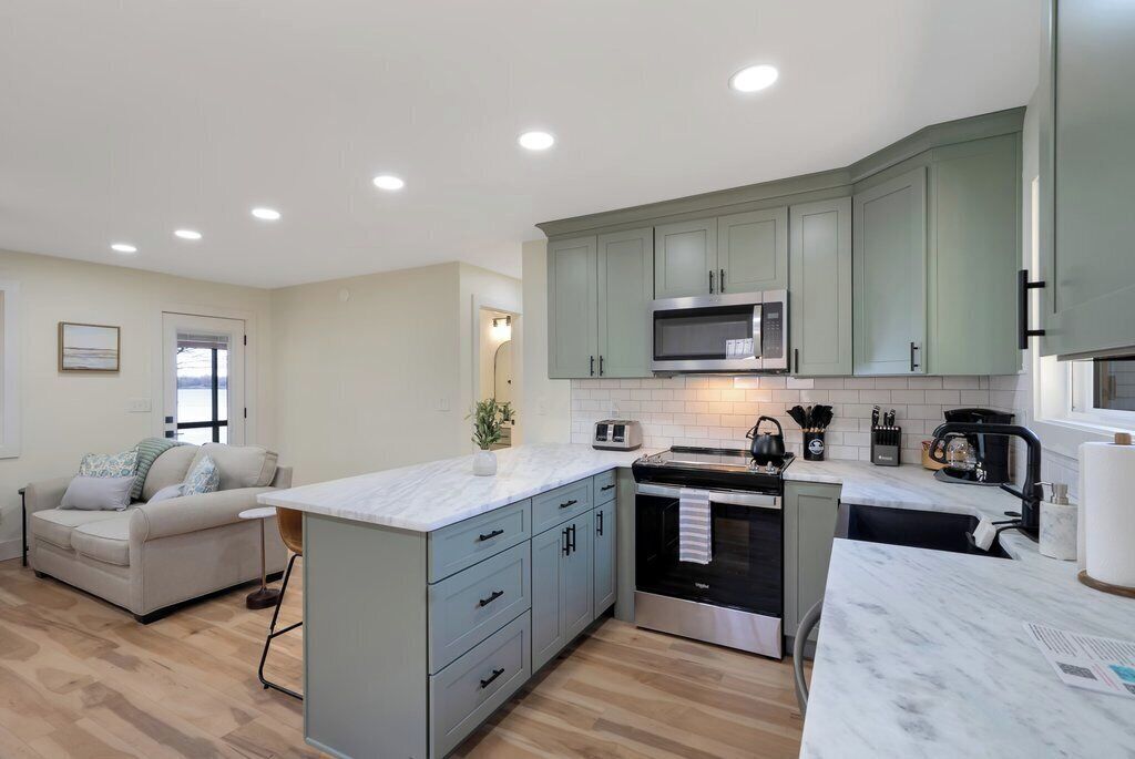 A modern kitchen with a central island, built-in appliances, and a dining area with a sofa.