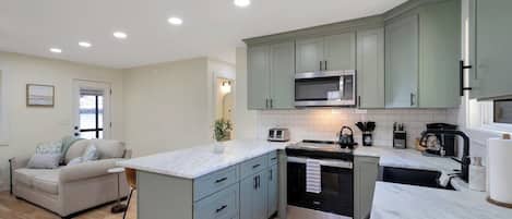Een moderne keuken met een centraal eiland, inbouwapparatuur en een zithoek met een bank.
