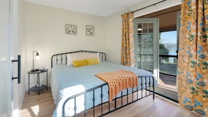 A bedroom with a bed, a bedside table with a lamp, a window with curtains, and a view of the outside. - Flat access - covered boat slip with dock-two car garage - year round water (Spring City)
