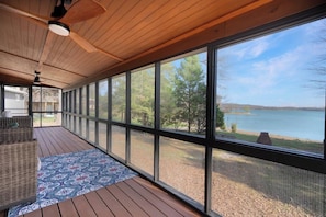 A covered deck with large windows, wicker furniture, and a patterned rug. - Flat access - covered boat slip with dock-two car garage - year round water (Spring City)