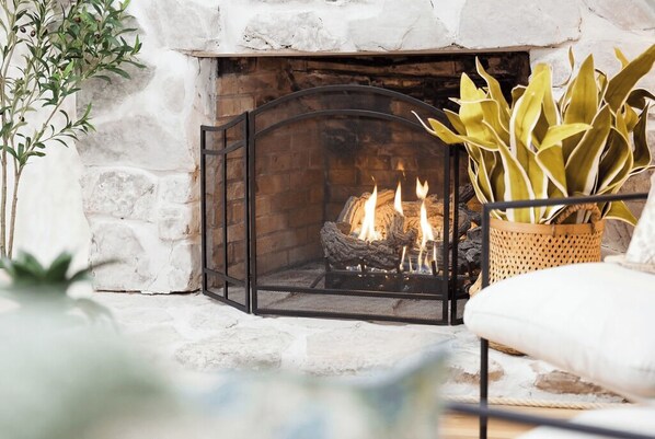 A stone fireplace with a fire, a white cushioned chair, and a woven basket with plants. - Flat access - covered boat slip with dock-two car garage - year round water (Spring City)