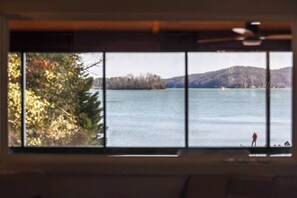 A view through a window with a person standing by the water. - Flat access - covered boat slip with dock-two car garage - year round water (Spring City)