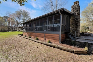 A modern building with large windows, a stone chimney, and a wooden deck. - Flat access - covered boat slip with dock-two car garage - year round water (Spring City)