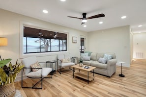 A modern living room with a sofa, chairs, a coffee table, and a large window with a view. - Flat access - covered boat slip with dock-two car garage - year round water (Spring City)