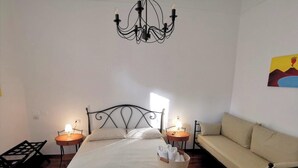 A bedroom with a bed, two bedside tables, a chandelier, a sofa, and a painting on the wall. - Comfortable rooms in the heart of Vomero, just a few meters from the subway. (Napoli)