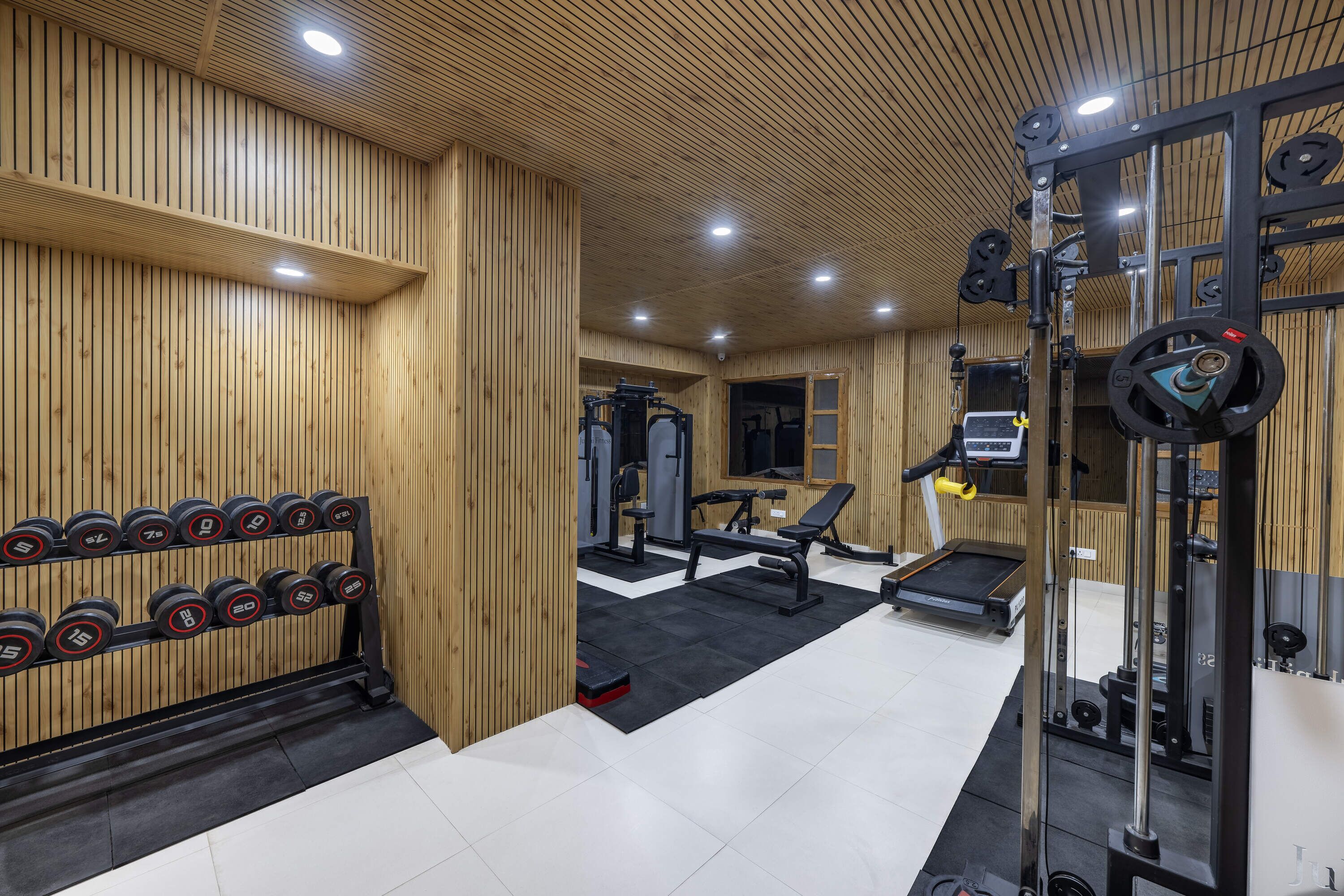 Una palestra con pareti in legno, una panca per pesi, manubri e un tapis roulant.
