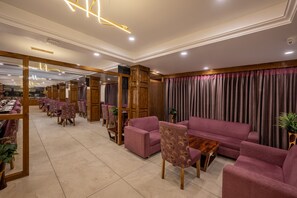 Un hall d’entrée spacieux au design moderne, comprenant un grand espace salon avec des canapés et des fauteuils, des éléments décoratifs en bois et un plafond bien éclairé.