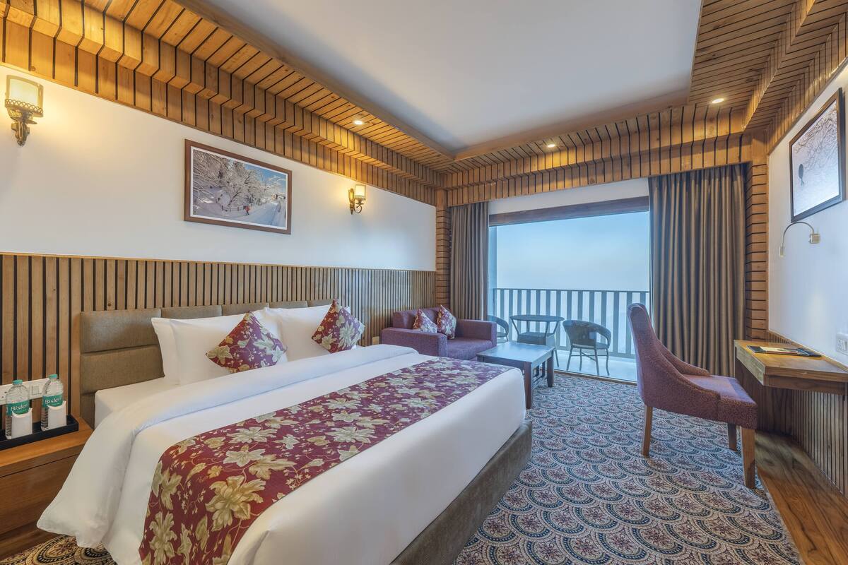 Une chambre d’hôtel avec un grand lit, un canapé, un bureau et une vue sur l’extérieur.