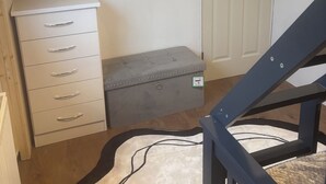 Una habitación con un armario blanco, un aparador gris, una puerta blanca y una escalera.