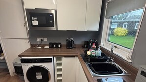 Una cocina compacta con lavadora, microondas, cafetera y lavamanos.