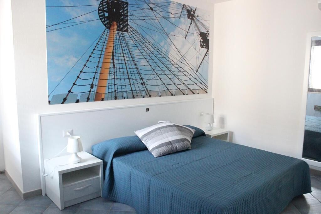 A bedroom with a bed, a nightstand, a lamp, and a wall-mounted picture of a Ferris wheel.