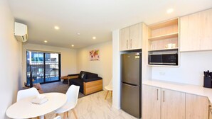A compact kitchen with a refrigerator, microwave, and wooden cabinets.