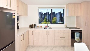A modern kitchen with a built-in oven, a stainless steel refrigerator, and a window with a city view.