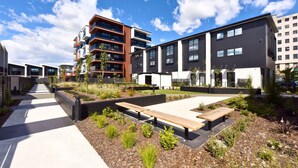A modern residential building with multiple floors, outdoor seating areas, and a well-maintained garden.