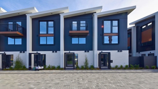 A modern multi-story residential building with balconies, large windows, and a paved entrance area. - Central 2BR Townhouse Close to Te Kaha Stadium (Christchurch)