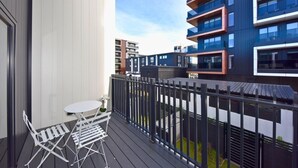 A balcony with a table and chairs, a view of modern buildings, and a metal fence. - Central 2BR Townhouse Close to Te Kaha Stadium (Christchurch)