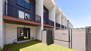A modern building with a flat roof, a balcony, and a gated entrance. - Stylish 2BR Retreat by Te Kaha Stadium (Christchurch)