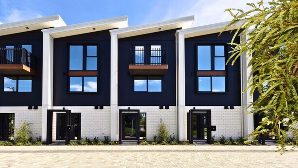 A modern three-story residential building with balconies, large windows, and a brick facade. - Stylish 2BR Retreat by Te Kaha Stadium (Christchurch)