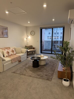 Ein modernes Wohnzimmer mit einer Couch, einem Couchtisch und einer Zimmerpflanze.