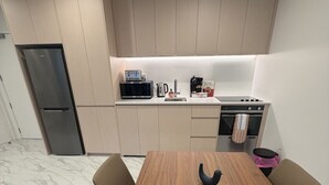 Une cuisine moderne équipée d’un four à micro-ondes, d’une cuisinière et d’un four encastrés. On y trouve une table à manger avec deux chaises, ainsi qu’un vase noir posé dessus.