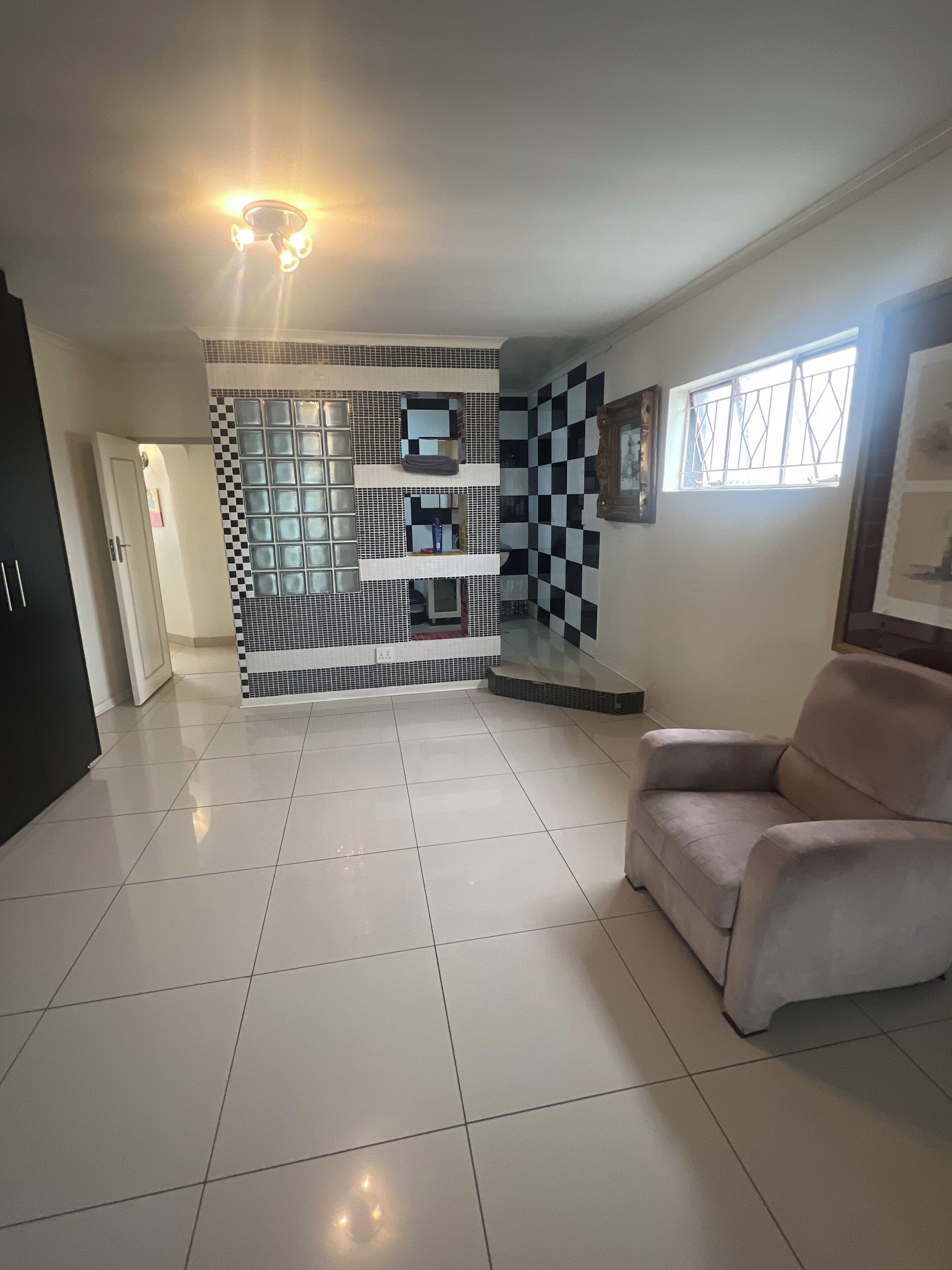 A spacious living area with a checkered wall design, a sofa, and a tiled floor.