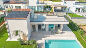 A modern two-story house with a swimming pool, large windows, and a well-maintained garden.