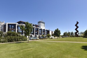A modern building complex with multiple floors, a clear sky, and a large abstract sculpture. - 2 Bedroom Delight near Te Kaha Stadium (Christchurch)