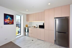 A modern kitchen with light wood cabinets, stainless steel appliances, and a large window. - 2 Bedroom Delight near Te Kaha Stadium (Christchurch)