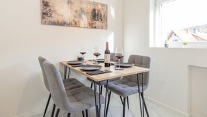 Comedor con una mesa preparada para cuatro personas, con una botella de vino tinto y copas.
