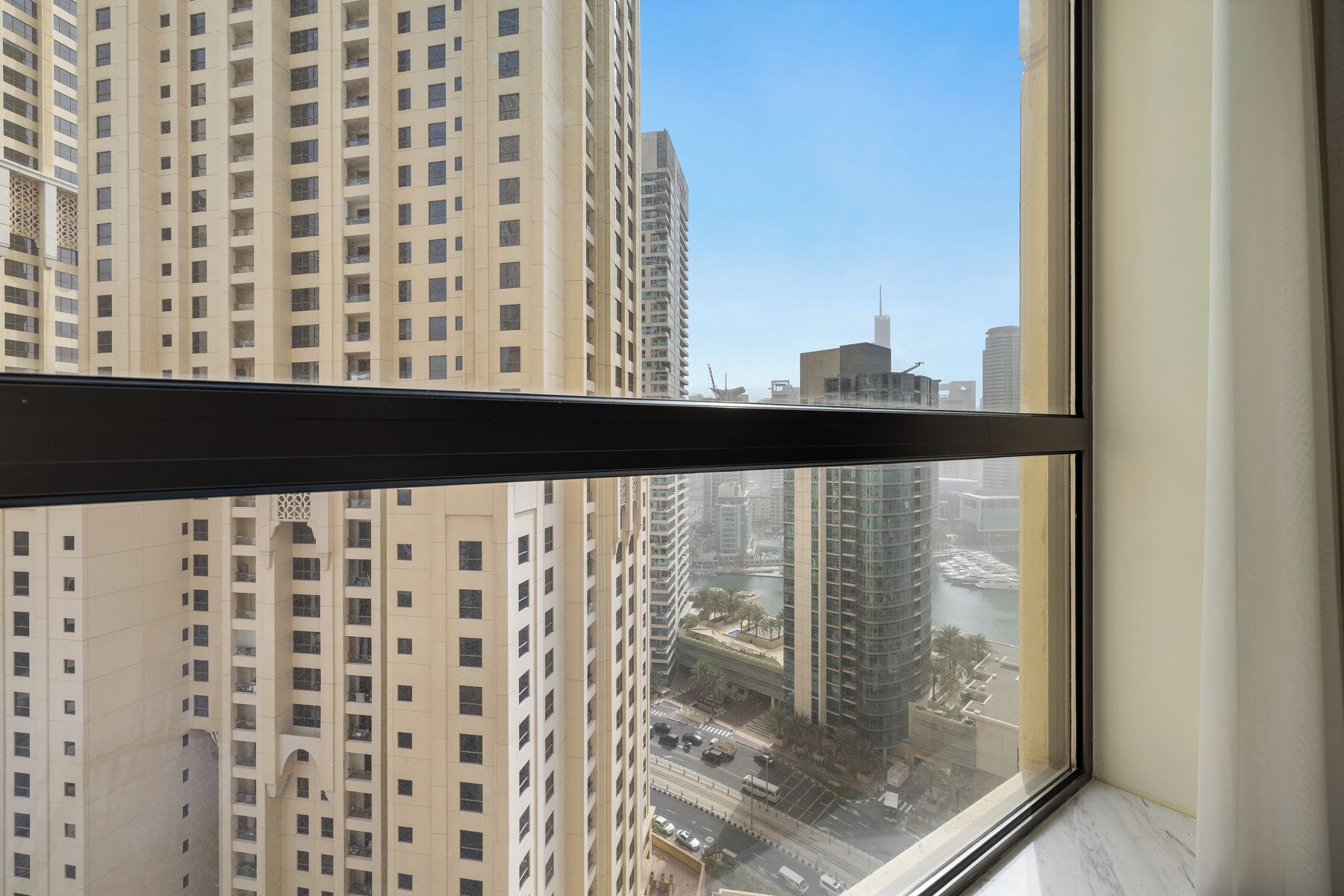 A view from a window of a high-rise building with multiple floors, a clear sky, and a distant view of a body of water and other buildings.