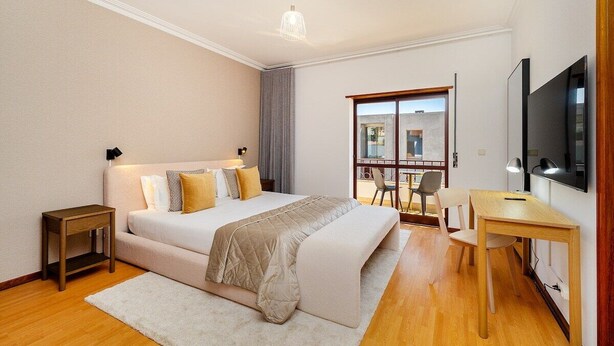 Een moderne slaapkamer met een groot bed, een bureau en een televisie.